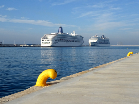 two cruise ships docked at the port face to face on a day with blue sky with a yellow bollardの写真素材