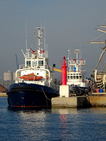 view of a tugboat moored in the harbor next to fishing boatsの写真素材