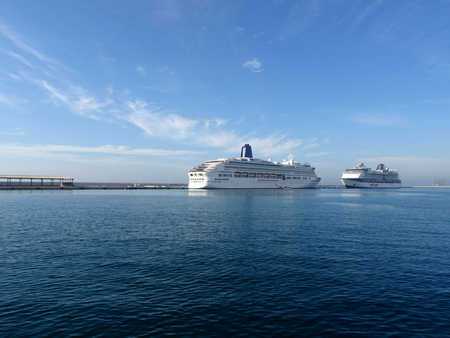two cruise ships docked at the port face to face on a day with blue skyの写真素材