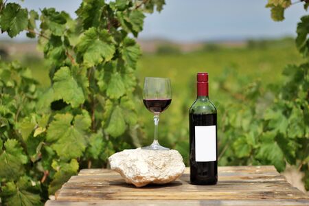 Still life of a red wine bottle, glass of wine on wooden plank with vineyards in the background. Vineyards of Spain.の写真素材