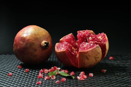 Still life of an open pomegranate with grains and seeds on dark background. Pomegranate variety fruit Mollar from Elche, Alicante.の写真素材