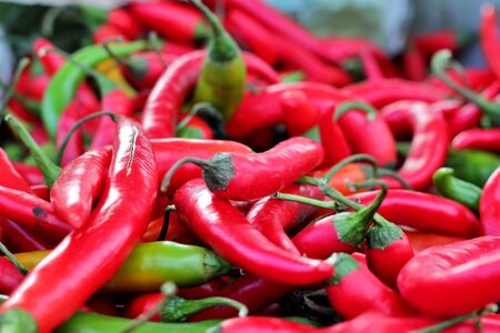 Close-up of red and green hot peppers at an outdoor market stall. Spicy recipes ingredient.の写真素材