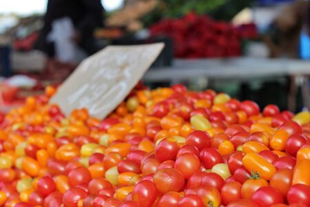 Close-up of mini cherry tomatoes at a market stall. Cultivation and natural products of proximity, ecological and bio. From the garden to your plate.の写真素材