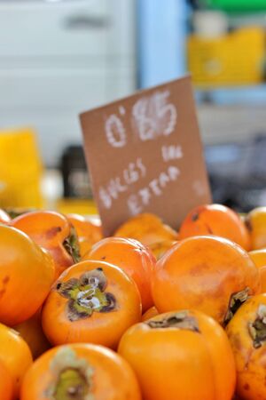 Bunch of kakis stacked in a market stall. Season's fruit. Proximity trade of natural, ecological and bio products. Alicante, Spain.の写真素材