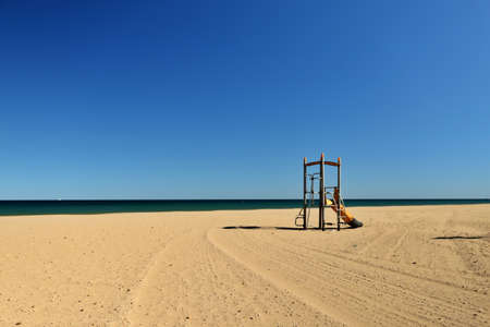 view of a lonely beach with a playground for children. coast of the mediterranean sea. Family friendly vacation spot. Alicante, Spain.の写真素材