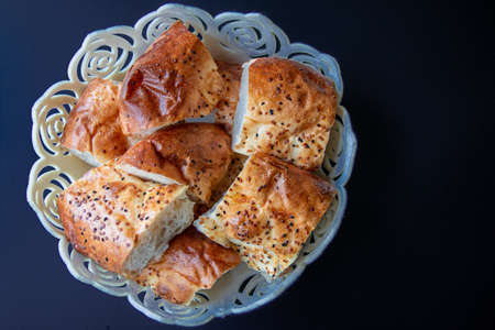 Bread with sesame seeds on a plate on a black background