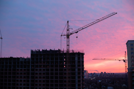 Apartment building site and crane in sunriseの写真素材