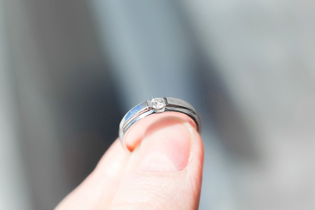 Macro photo of white gold ring with a diamond in the fingers closeup