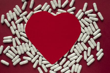 Red paper heart on a background of pills. Cardiology concept. Copy space for textの写真素材