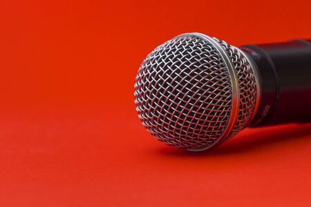 Black karaoke microphone on a red background close-up