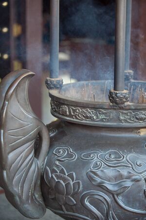 Temple incense vase with smoking sticks insideの写真素材