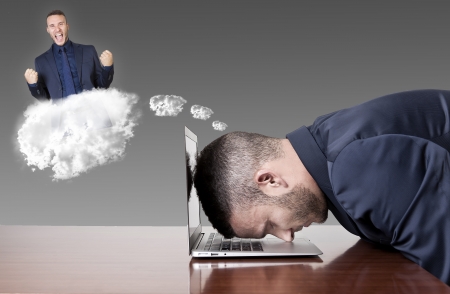 businessman dreaming success with head on laptopの写真素材