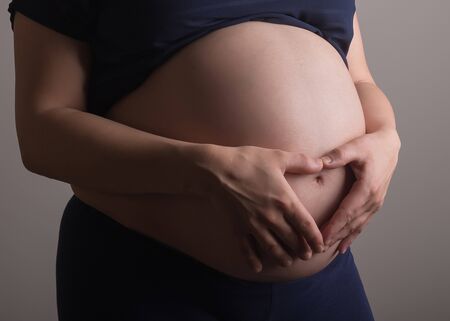 pregnant woman touching her belly with hands