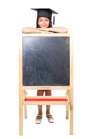 Caucasian girl with a university cap leaning on blackboardの写真素材