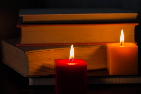 Burning candles against booksの写真素材