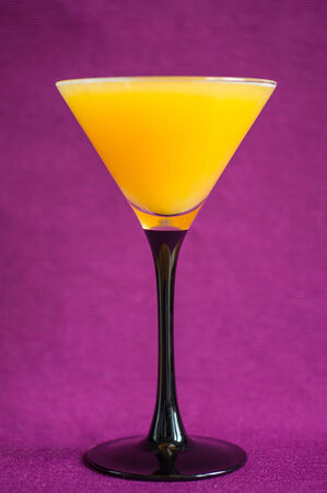 Orange juice in a glass for martini on a violet backgroundの写真素材