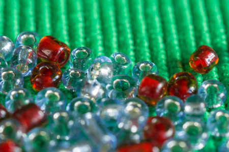 The scattered beads of red and gray color on a green backgroundの写真素材