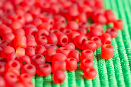 The scattered beads of red color on green fabricの写真素材