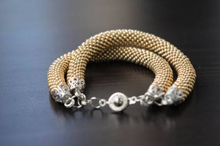 Knitted bracelet of gold color on a wooden backgroundの写真素材