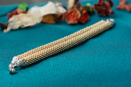 Bracelet of gold color on a textile backgroundの写真素材