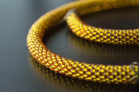 Fragment of a knitted necklace from beads of yellow colorの写真素材