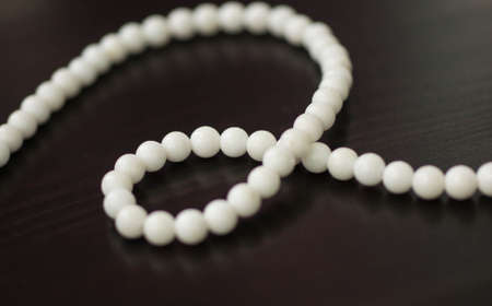 Necklace from stone white beads on a dark surface close upの写真素材