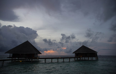 Sunset in the Maldives with a view of the ocean, sky and bungalowsのeditorial素材