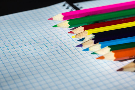 Colored pencils lying on an open notebook