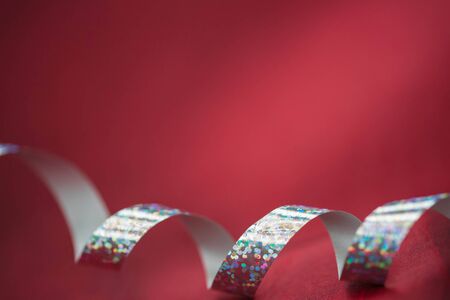 Shiny silver gift ribbon on a dark red backgroundの写真素材