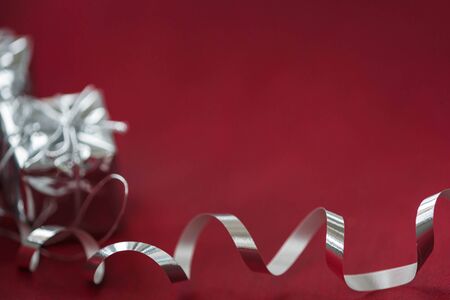 Silver ribbon and gift boxes on a burgundy backgroundの写真素材