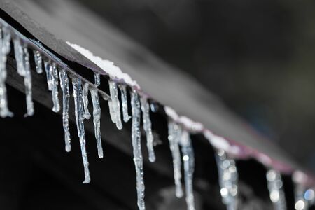 Icicles on an old iron roof on a sunny dayの写真素材