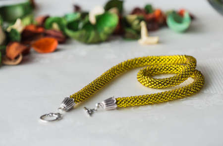 Shining yellow beaded crochet necklace on textile backgroundの写真素材