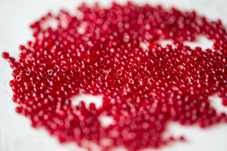 Seed beads of red color on the textile background close upの写真素材