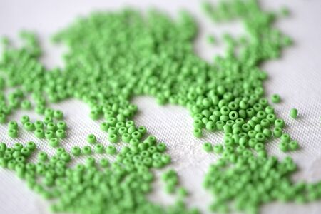 Scattered seed beads of light green color on a textile backgroundの写真素材