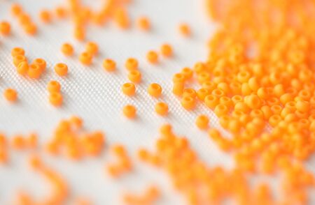 Seed beads of orange color on textile background