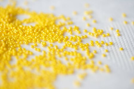 Seed beads of yellow color on textile background close upの写真素材
