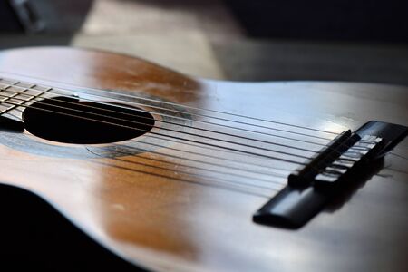 The old guitar and music books illuminated by the sunの写真素材