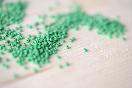 Scattered seed beads of green color on the wooden backgroundの写真素材