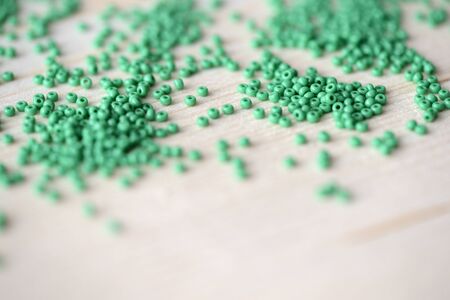 Scattered seed beads of green color on the wooden backgroundの写真素材