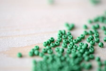 Scattered seed beads of green color on the wooden backgroundの写真素材