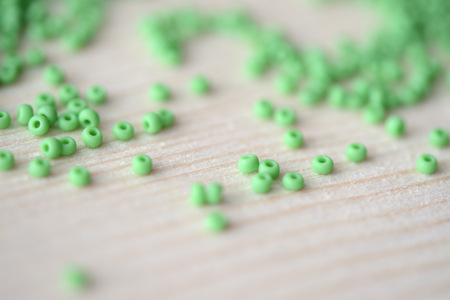 Scattered seed beads of light green color on a wooden backgroundの写真素材