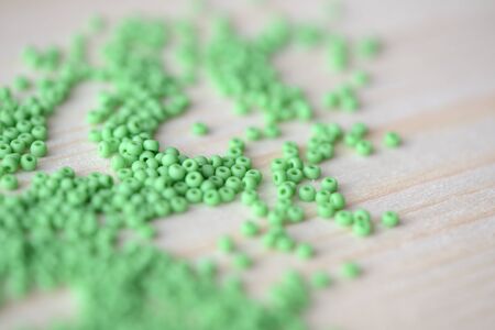 Scattered seed beads of light green color on a wooden backgroundの写真素材