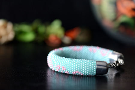 Mint beaded bracelet with floral print on a dark backgroundの写真素材