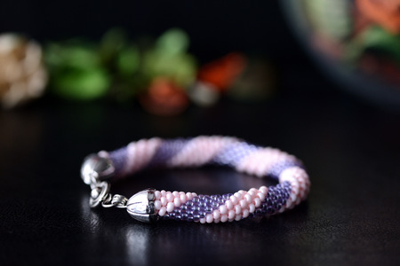 Beaded bracelet of pink and lilac color on a dark backgroundの写真素材