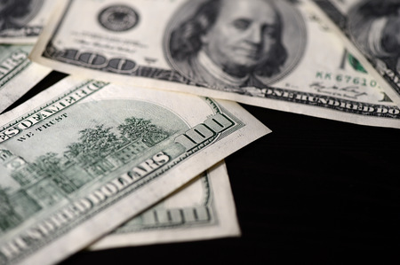 A pack of hundred dollar bills on a dark backgroundの写真素材