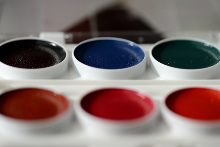 Box with watercolors and white paper close up