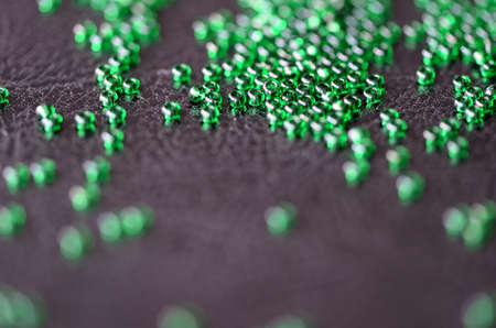 Transparent green seed beads on a dark leather backgroundの写真素材