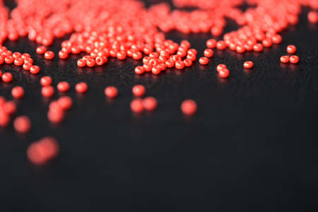 Red seed beads scattered on a dark backgroundの写真素材