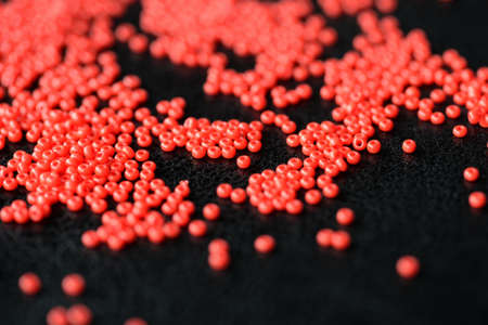 Red seed beads scattered on a dark backgroundの写真素材