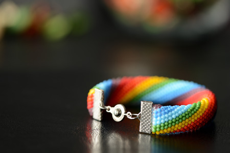 Bead crocheted bracelet of a rainbow colors on a dark backgroundの写真素材